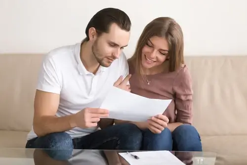 Happy couple holding a no income verification mortgage and loan contract